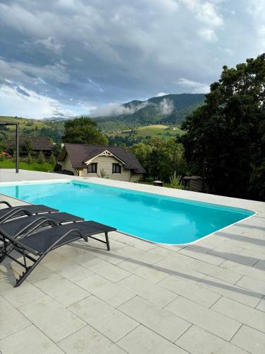 a swimming pool with two lounge chairs next to a house at Вілла у горах in Krasnik