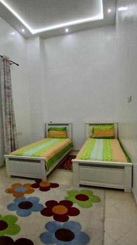 two beds in a room with a rug at Aéroport appartement in Tangier
