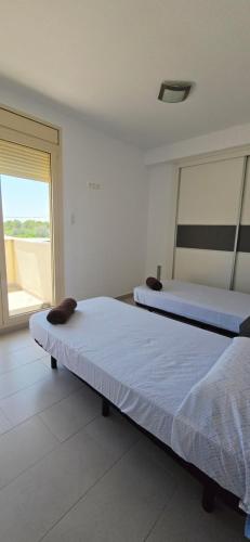 two beds in a room with a large window at Vistamar in Les tres Cales
