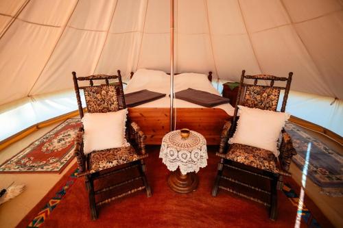 a room with two chairs and a bed in a tent at Pyramid Retreat in Sebeş