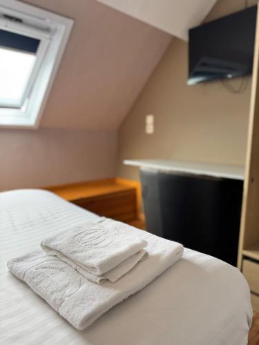 a pair of towels sitting on top of a bed at Family Hôtel in Wavre
