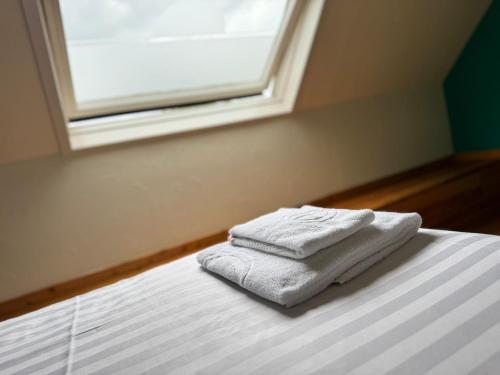 two towels sitting on a bed in a room with a window at Family Hôtel in Wavre