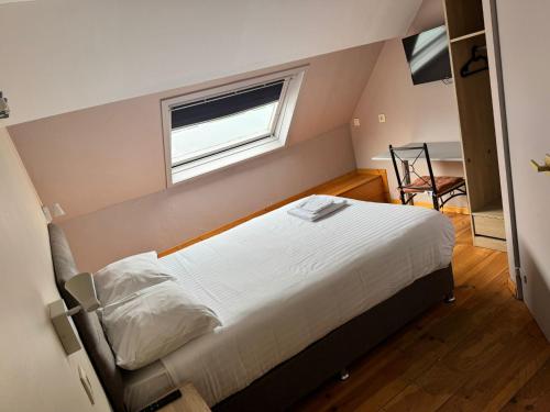 a bedroom with a bed and a window and a chair at Family Hôtel in Wavre