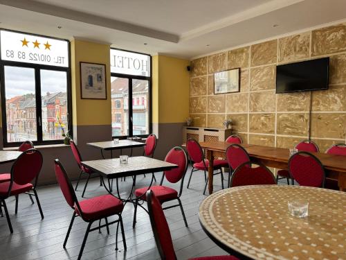 a restaurant with tables and chairs and a flat screen tv at Family Hôtel in Wavre