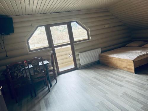 an attic room with a bed and a window at Domik Zubanicha in Kelechin