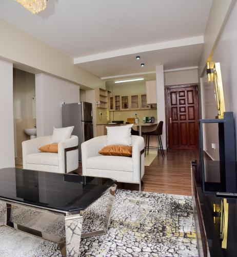 a living room with two white chairs and a tv at Davinia Haven in Athi River