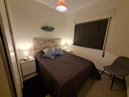 a bedroom with a bed and a chair and a blackboard at T2 Praia de Faro in FAO
