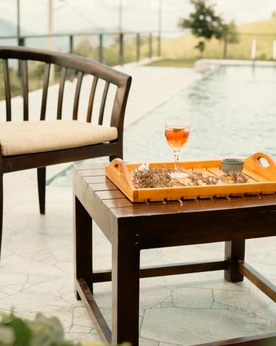 a tray with a glass of wine on a table next to a pool at The Aurelia in Gampola