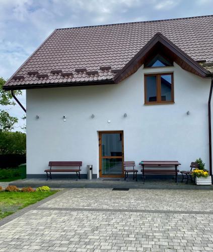 two benches in front of a white house at Zielona Ostoja - Pokoje i Apartamenty in Nowa Sarzyna