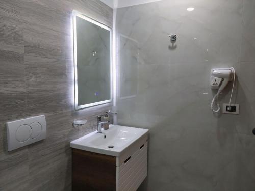 a white bathroom with a sink and a mirror at Qeparo Antonio Rooms in Qeparo
