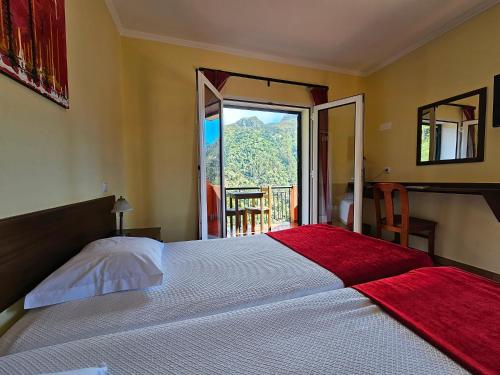 a bedroom with a large bed with a large window at Valley View Hotel Encumeada in Senhora do Rosário