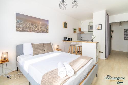 Cet appartement comprend une chambre avec un lit blanc et une cuisine. dans l'établissement Heliot - Hypercentre - Proche du métro, à Toulouse