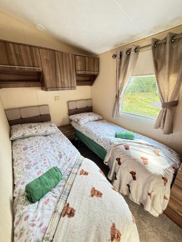 two beds in a small room with a window at Winchester 34 in Edzell