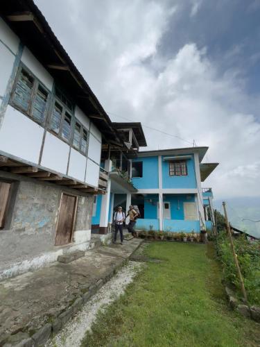 Dos personas paradas afuera de una casa azul en Ecoventure Todey Tangta, en Thode