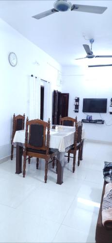 a dining room with a white table and chairs at Alappuzha Family Vacation Villa - LAYANILA in Alleppey