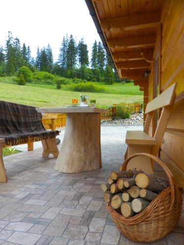 a picnic table and a basket of logs on a patio at Domek pod Howyzem in Łapsze Niżne
