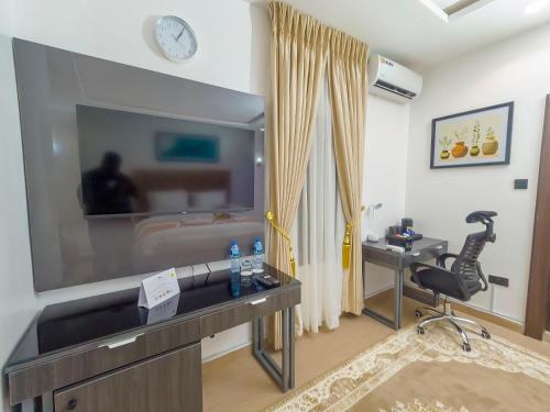 a room with a tv and a desk and a chair at Morgan Hill Residence in Abuja