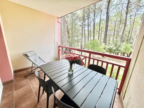 une table avec un vase de fleurs sur un balcon dans l'établissement T2 Lacanau - Calme & Confort - Pinède, Piscine, Lac et Océan, à Lacanau