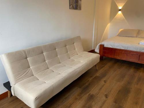 a white couch in a room with a bed at Aparta hotel Montecristo Suites in Quimbaya