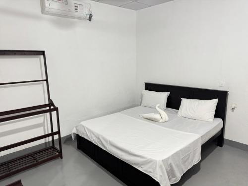Schlafzimmer mit einem Bett mit weißer Bettwäsche und weißen Kissen in der Unterkunft TravelLodge Eco in Arugam Bay