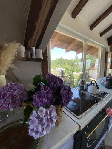 a vase of purple flowers on a counter in a kitchen at Kuća sa bazenom Sarajevo - Lavanda Estate in Sarajevo