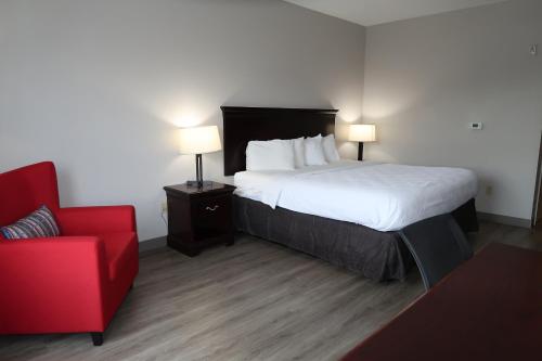 a hotel room with a bed and a red chair at Country Inn & Suites by Radisson, Tallahassee-University Area, FL in Tallahassee