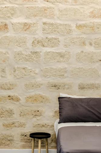a bedroom with a brick wall with a bed and a stool at Marenda - B&B in Bari