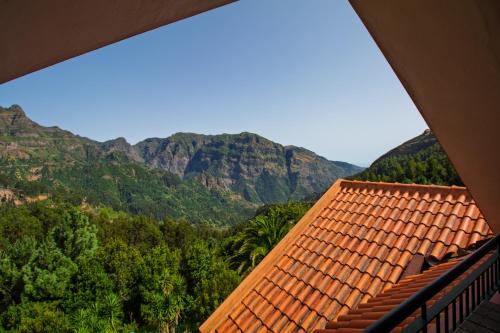 a view of a roof of a house with mountains in the background at Valley View Hotel Encumeada in Senhora do Rosário