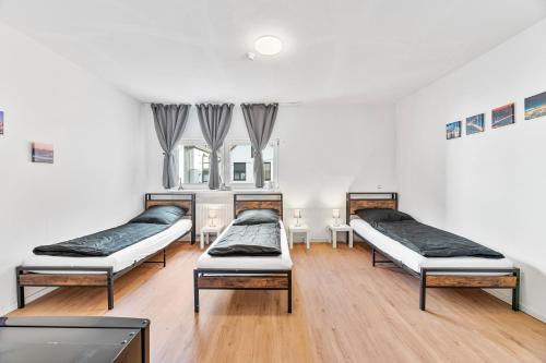 three beds in a room with wooden floors and windows at ZF02 Monteurzimmer Stuttgart - Platz für bis zu 20 Personen im Haus - Mehr Apartments und Zimmer verfügbar LS-CrewComfort in Stuttgart