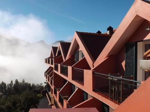 a red building with mountains in the background at Valley View Hotel Encumeada in Senhora do Rosário
