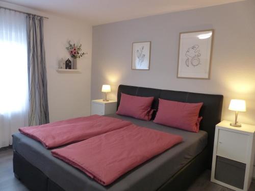 a bedroom with a bed with pink sheets and two lamps at Ferienwohnung Jesse in Braunlage