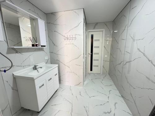 a white bathroom with a sink and a mirror at Guest hause in Naryn in Tashbulak