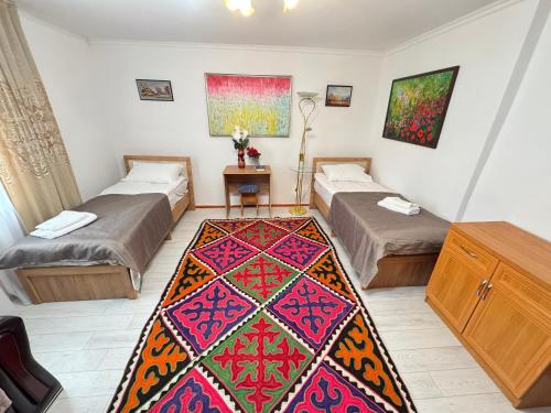 a room with two beds and a rug on the floor at Guest hause in Naryn in Tashbulak