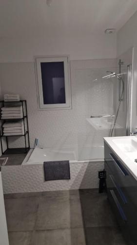 a bathroom with a shower and a tub and a sink at Au cœur des pierres dorées in Bully