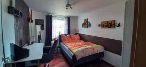 a bedroom with a bed and a desk with a television at Ferienwohnung Fichtelgebirge in Brand