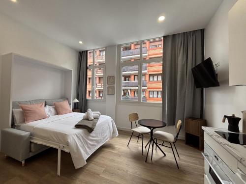 a bedroom with a bed and a table and two windows at Gabika Apartment 1 in Bilbao