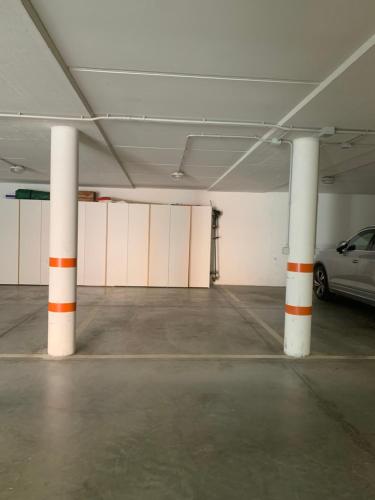 an empty parking garage with white columns and a car at Chalet le Dolomiti in Borca di Cadore