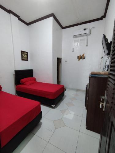 a room with two beds and a tv in it at Krui penginapan jokowi in Krui