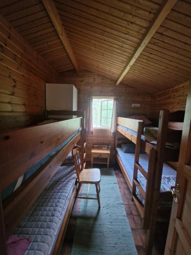 a room with two bunk beds and a chair in a cabin at Lidens Stugby in Vaggeryd