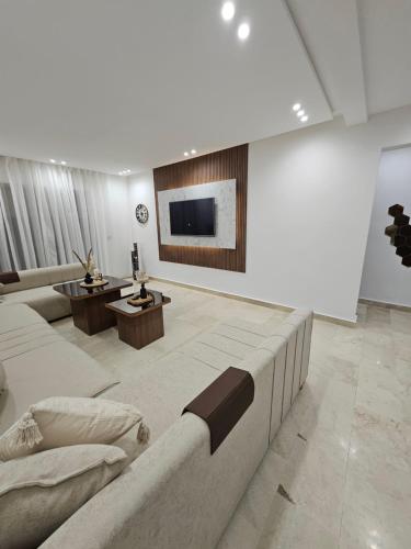 a large living room with a couch and a tv at Appartement luxueux et cosy Marina Saïdia in Saidia 