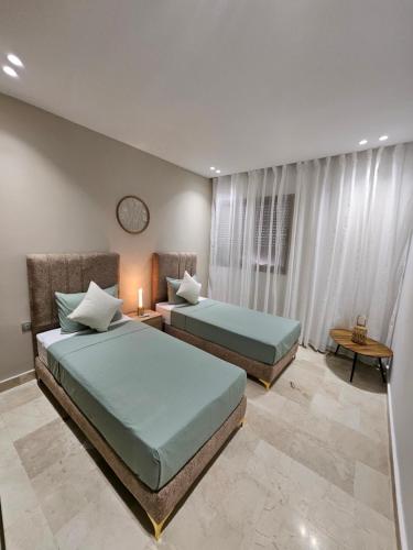 a bedroom with two beds and a table with a clock at Appartement luxueux et cosy Marina Saïdia in Saidia 