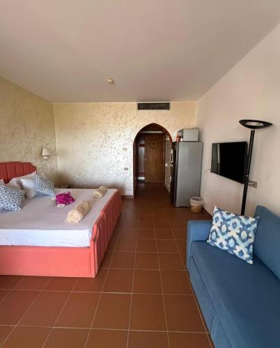 a room with a bed and a couch and a tv at Domina Coral Bay Private Studios - Oasis - Blocco 34 in Sharm El Sheikh