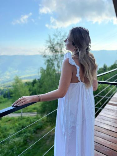 a woman in a white dress standing on a deck at Vista Krasiya in Vyshka