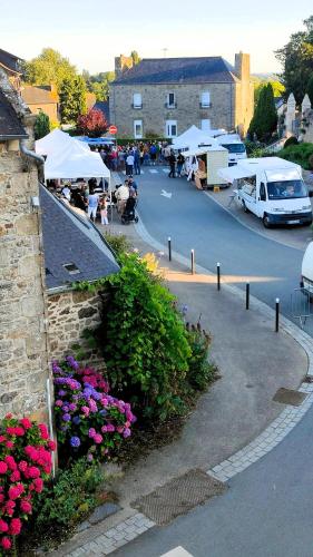 a parking lot with tables and white umbrellas and flowers at L'Ancienne Saboterie in Plorec-sur-Arguenon