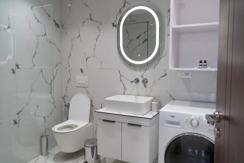 a white bathroom with a toilet sink and a mirror at Villa Merkaj in Sarandë
