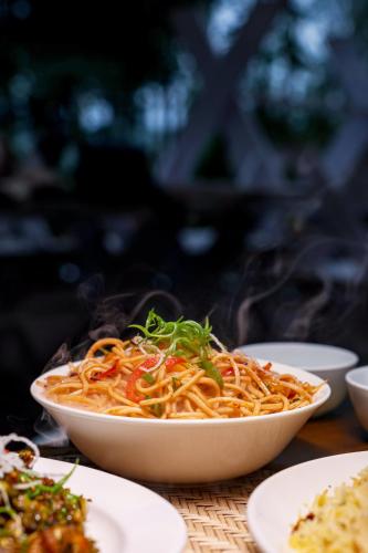 a bowl of noodles with vegetables on a table at Shoonya Farm Retreat in Belgaum
