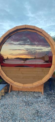 a circular wooden bed with a sunset in the background at Czill Beczki in Mucharz