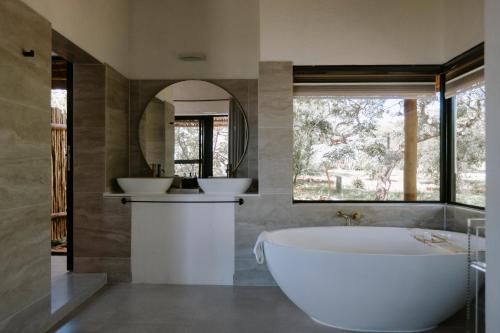 a bathroom with a tub and two sinks and a mirror at Rhino Plains in Welgevonden Game Reserve