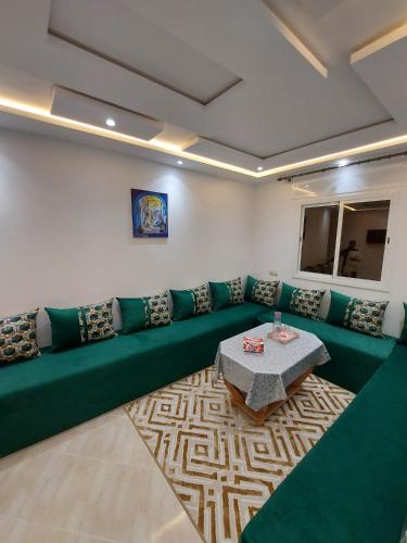 a living room with a green couch and a table at Arizona Hotel in Martil