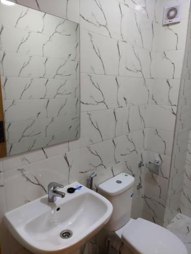 a white bathroom with a toilet and a sink at Arizona Hotel in Martil